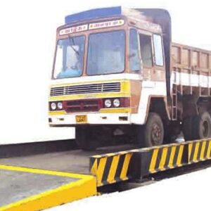 Truck on a pitless weighbridge with safety barriers on both sides for weight measurement.