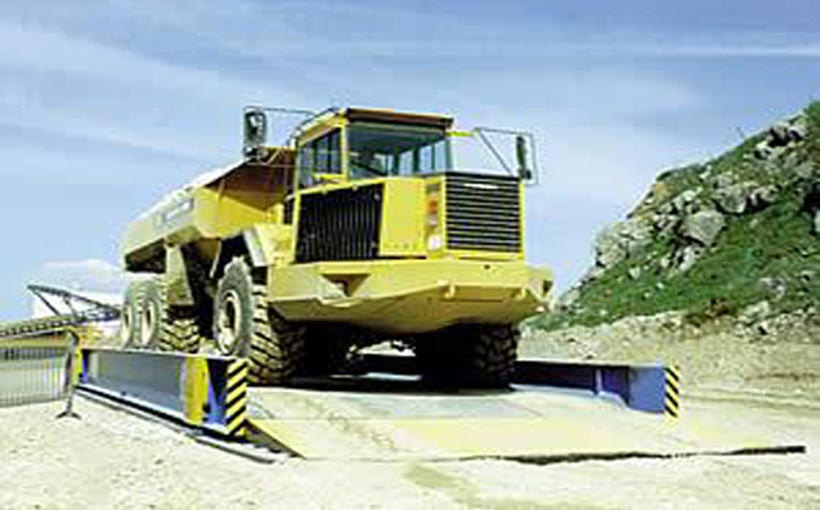 Truck on a Portable Weighbridge with safety barriers on both sides for weight measurement.